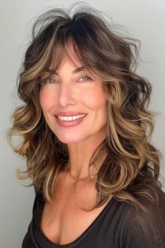Try on this stylish wavy and highlighted hairstyle, featuring rich layers and a dynamic blend of brown tones that beautifully frame the face.