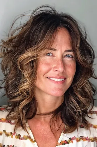Try on this medium-length wavy hairstyle with light balayage highlights, featuring a natural blend of dark and light brown tones.