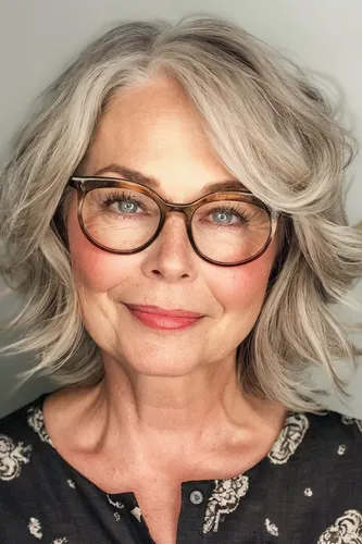Try on this elegant wavy hairstyle that blends gray and blonde tones, styled in a layered, voluminous look. Ideal for those wanting to showcase a sophisticated and trendy appearance.