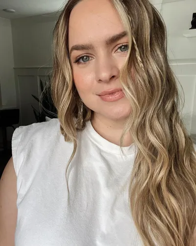 try on this wavy, blonde hairstyle that cascades softly around the face, providing both volume and elegance