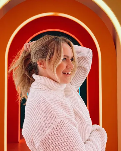 Try on this casual, messy ponytail hairstyle featured in the image with a playful touch as the person adjusts their hair