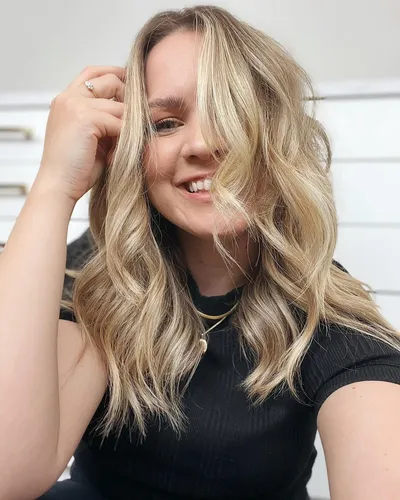 Try on this style featuring wavy, blonde highlighted hair with medium length.