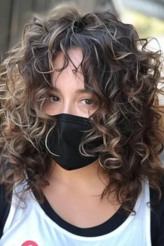 Try on this voluminous multi-toned curly hairstyle that effortlessly frames the face, giving a lively and dynamic appearance.