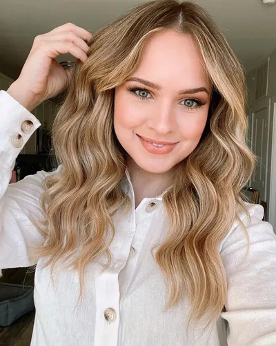 Try on this charming wavy, long hairstyle framing a cheerful face