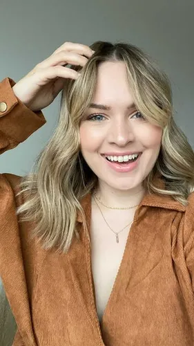 Try on this wavy, medium-length hairstyle featuring light brown highlights and soft waves that enhance the texture.