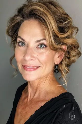 Try on this elegant, curly updo hairstyle with softly swept up curls and subtle highlights, adding a sophisticated and graceful look. The hairstyle adds dimension and texture, perfect for enhancing facial features.