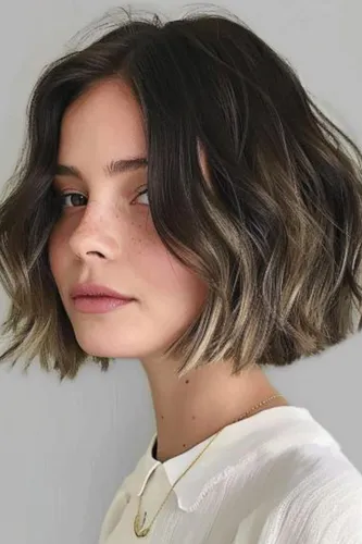 Try on this chic shoulder-length wavy hairstyle featuring blended brown highlights.