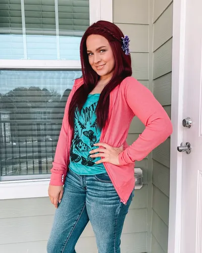 Try on this vibrant long, straight hairstyle with a side part, accentuated by a purple flower hair accessory.