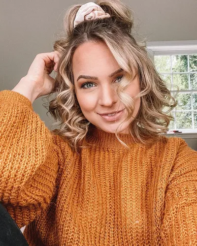 Try on this playful and trendy medium-length curly hairstyle, adorned with a chic hair scrunchie on top, offering a fun and youthful vibe.