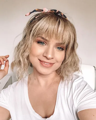 Try on this wavy hairstyle with bangs, complemented by a floral headband for a charming and fresh look.