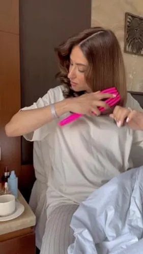 Try on this sleek, straight, mid-length hairstyle that features a smooth texture with even ends. The person is adjusting their hair, which enhances the neat appearance of the hairstyle.