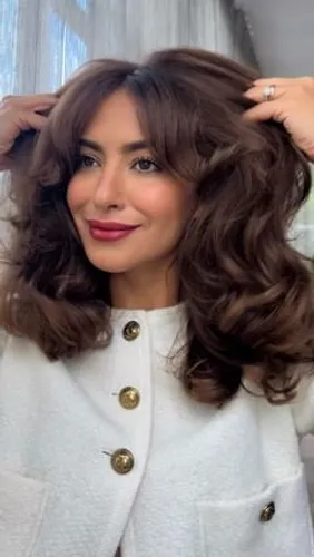 Try on this voluminous, wavy hairstyle that frames the face beautifully, enhancing elegant features