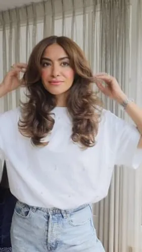Try on this hairstyle featuring long, subtly highlighted waves with layers adding volume around the face.