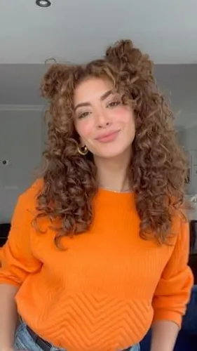 Try on a voluminous curly hairstyle with bouncy curls framing the face. Perfect for a lively and youthful appearance.