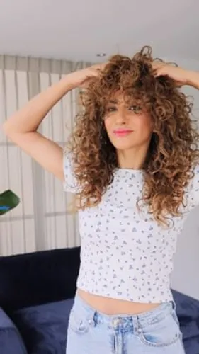 Try on a hairstyle featuring voluminous, shoulder-length curly hair, adding a dynamic and textured look.