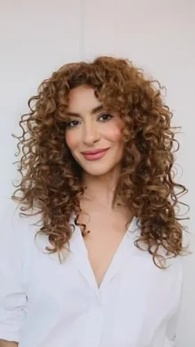 Try on a voluminous curly hairstyle with dense, well-defined curls cascading around the face.