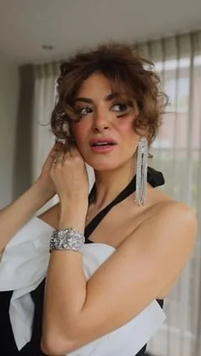 Try on a curly hairstyle as seen on a person in an elegant setting with soft lighting.