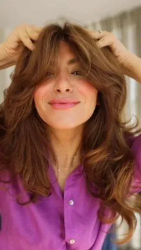 try on a long, wavy hairstyle with a voluminous look, styled in a casual manner. The hair has a natural brown color and demonstrates a dynamic flow, exhibiting waves that add texture to the look.