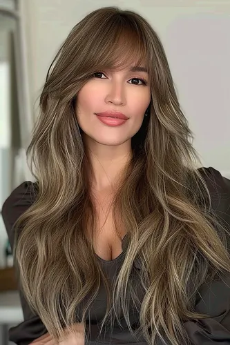 Try on this long wavy hairstyle that flows beautifully with shades of brown and subtle blonde highlights.