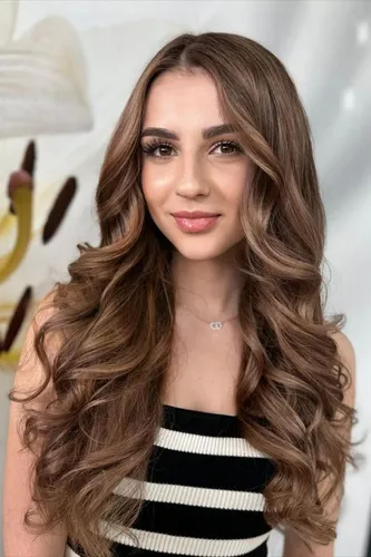 Try on this luxurious long wavy hairstyle with soft curls and subtle brown tones.