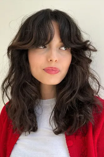 Try on this voluminous wavy hairstyle with bangs, creating a charming and fresh look