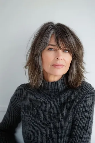 Try on a fashionable shaggy, layered hairstyle with subtle highlights. This look features medium-length hair with a natural wave and texture, accentuated by a fringe that softly curtains the eyes, providing a versatile and modern appearance.