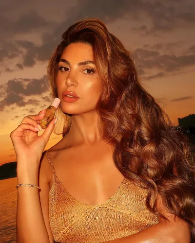 Try on this long, thick curly hairstyle that cascades elegantly with voluminous curls, perfect for a glamorous evening look.