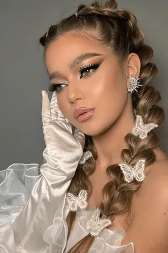 Try on this intricate braided hairstyle, featuring multiple braiding styles that intertwine along the head and cascade into a long, voluminous braid adorned with butterfly accessories.