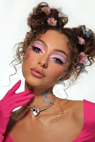 Try on this playful hairstyle featuring curly hair gathered into small buns, adorned with pink and blue flowers.