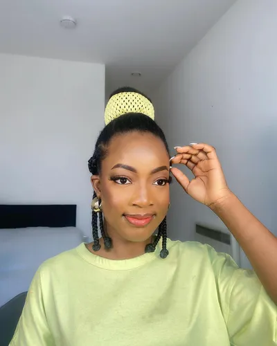 Try on this elegant hairstyle featuring a neat braided bun on top, complemented by two hanging braided ponytails at the sides.