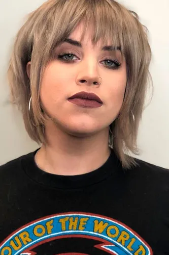 Try on this stylish choppy bob hairstyle with a heavy fringe that frames the face. The hair color is a mix of ash blonde and light brown tones.