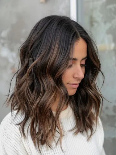 Try on this wavy, ombre hairstyle with dark roots transitioning to lighter tips, creating a soft, natural gradient effect.