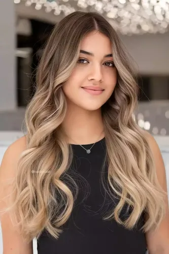Try on this long wavy ombre hairstyle with subtle blonde highlights flowing through brown strands. The hair gracefully frames the face, cascading over the shoulders. Perfect for a refined yet effortless look.