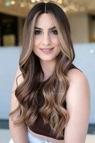 Try on this elegant long wavy hairstyle with subtle highlights, perfect for a soft and natural look