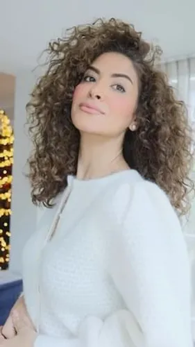 Try on this medium-length curly hairstyle that adds volume and texture, perfect for a stylish, bouncy look.