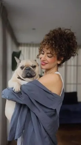 Try on a curly hairstyle as seen on the woman embracing a pug. Her curly locks are neatly styled to enhance her cheerful demeanor.