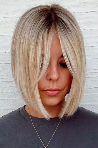 Try on this sleek blonde bob hairstyle. The hair is neatly cut at jaw-length with a straight, smooth texture, having darker roots that blend into lighter blonde tones.