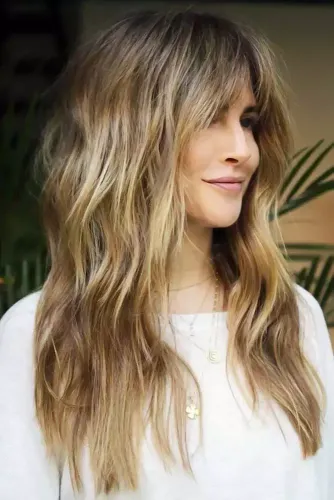 Try on this elegant long wavy hairstyle with blonde highlights, perfect for adding a touch of softness and volume.