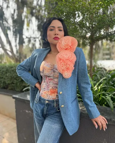 Try on this short curly hairstyle, showcased by a single person standing outdoors with a focus on their fashionable attire, including a blue blazer and light blue jeans.