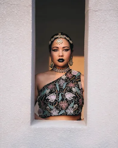 Try on the ornate jewelry style, including a detailed and decorative choker necklace with matching earrings, subtly reflecting cultural fashion. The outfit is a sleeveless top adorned with intricate floral embroidery.