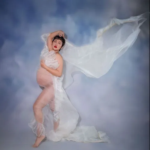 Try on a short and wavy hairstyle as seen on the woman in the image. The hairstyle adds a dynamic touch to her elegant pose wrapped in flowing fabric.