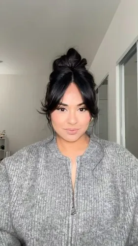 Try on a casual yet stylish messy bun hairstyle paired with face-framing bangs.