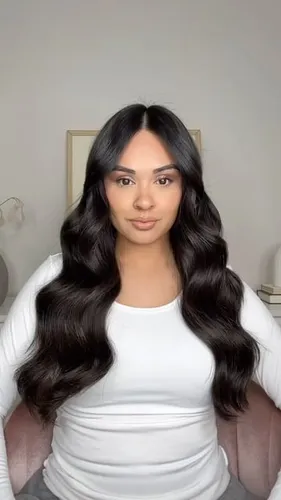 Try on this long wavy hairstyle featuring large glossy waves that cascade beautifully down the back.