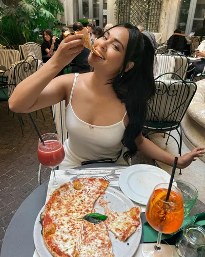 Try on a long, black hairstyle as the woman enjoys a slice of pizza at an outdoor café setting.