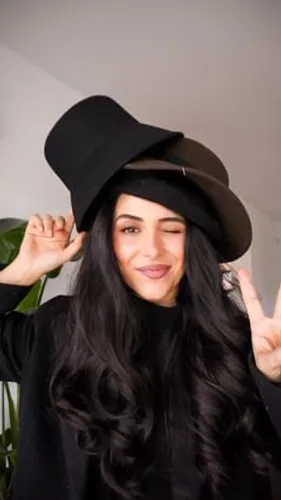 Try on this hairstyle featuring long, wavy hair complemented by a stylish black hat.