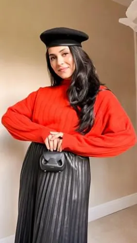 Try on this long, black hairstyle. The person is dressed in vibrant clothing and accessorized stylishly, showcasing flowing dark hair draped over one shoulder, complementing her stylish outfit.