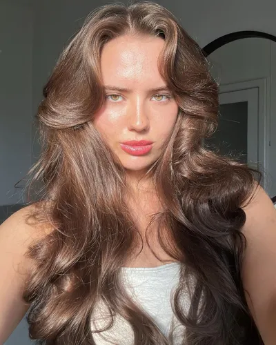 Try on this elegant long wavy hairstyle that cascades smoothly down, enhancing a graceful and voluminous look.