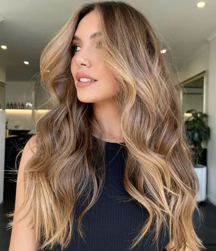 Try on this hairstyle featuring long wavy hair with a seamless ombre from brunette to blonde, cascading in loose curls.