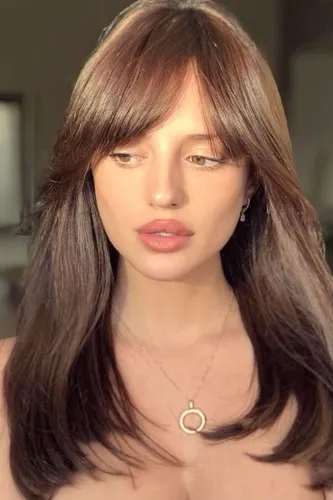 Try on a hairstyle with long, brown hair featuring soft layers and bangs partially covering the forehead.