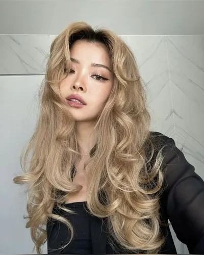 Try on this luxurious wavy blonde hairstyle that frames the face beautifully with its voluminous curls and light blonde hues.
